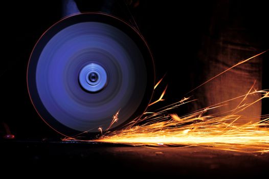 Worker cutting metal with grinder. Sparks while grinding iron