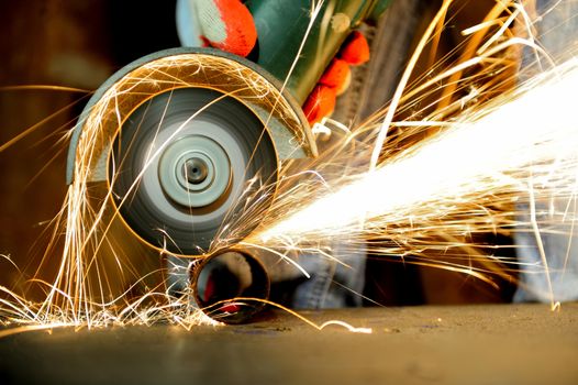 Worker cutting metal with grinder. Sparks while grinding iron