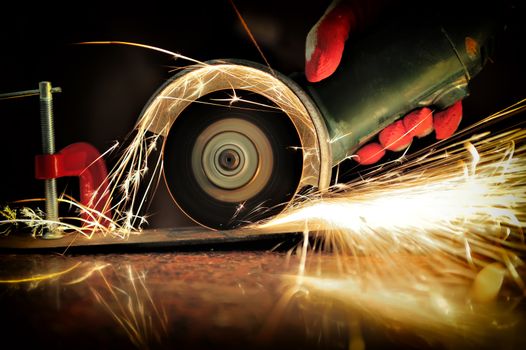 Worker cutting metal with grinder. Sparks while grinding iron