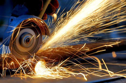 Worker cutting metal with grinder. Sparks while grinding iron