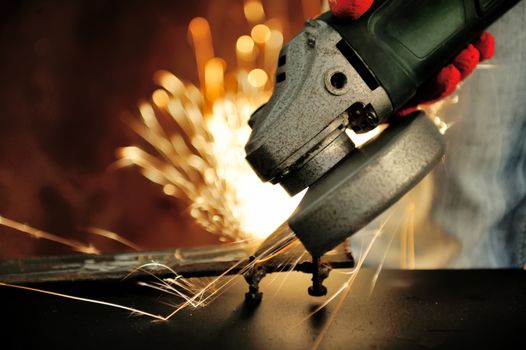 Worker cutting metal with grinder. Sparks while grinding iron