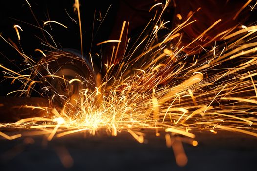 Worker cutting metal with grinder. Sparks while grinding iron