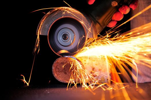 Worker cutting metal with grinder. Sparks while grinding iron