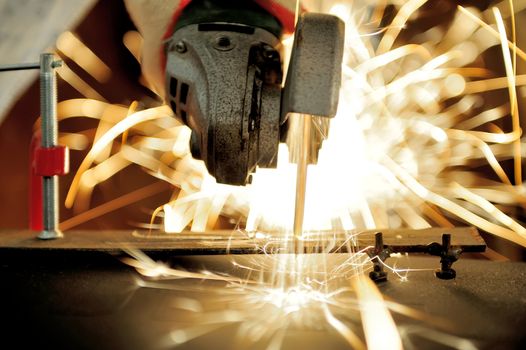 Worker cutting metal with grinder. Sparks while grinding iron