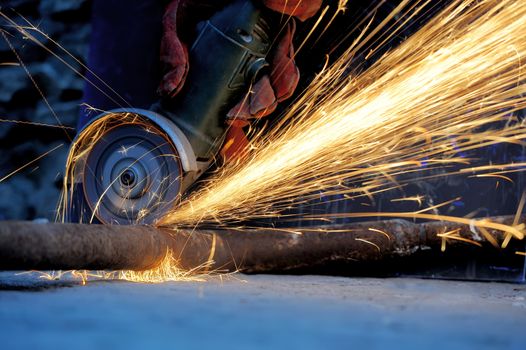 Worker cutting metal with grinder. Sparks while grinding iron