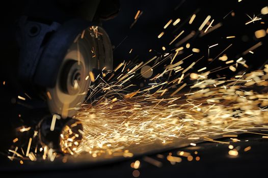 Worker cutting metal with grinder. Sparks while grinding iron