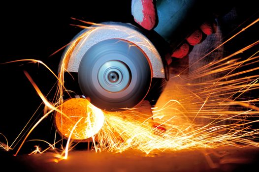 Worker cutting metal with grinder. Sparks while grinding iron