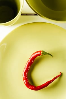 Top view red hot pepper on green dish over white wood. Vertical image.