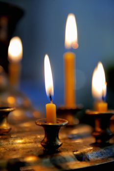 Burning candles in sconces on black blue background