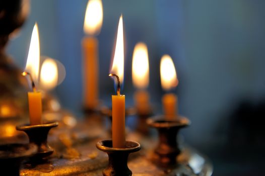Burning candles in sconces on black blue background
