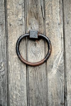 Ancient wooden gate with door knocker rings close-up