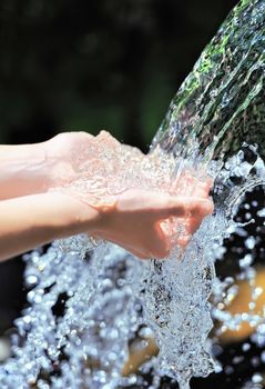 Woman's hands with water splash on dark background