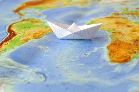 Paper boat on a background map of the world. Traveling concept