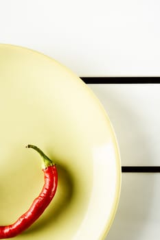 Top view red hot pepper on green dish over white wood. Vertical image.