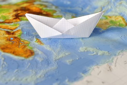 Paper boat on a background map of the world. Traveling concept