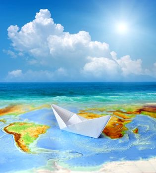 Paper boat on a background map of the world. Traveling concept