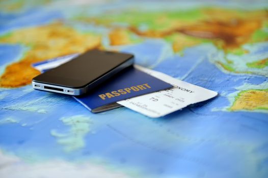 Passport, ticket, phone on a background map of the world. Traveling concept