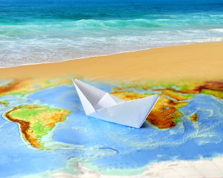 Paper boat on a background map of the world. Traveling concept