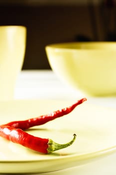  Red hot pepper on green dish over white wood. Vertical image.