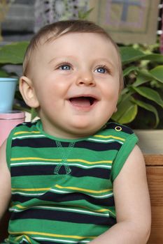 Cute baby boy outside in the garden wearing green outfit