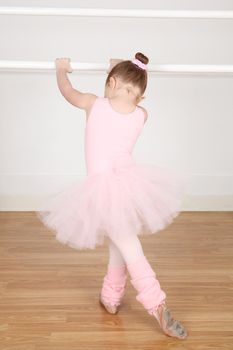 Little ballerina wearing a tutu dancing at the barre