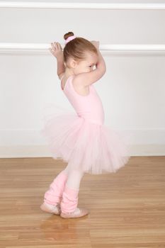 Little ballerina wearing a tutu dancing at the barre