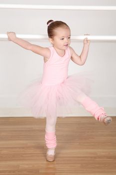Little ballerina wearing a tutu dancing at the barre