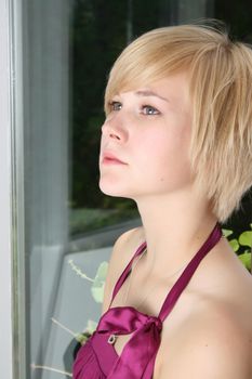 Beautiful blond female leaning against a door, expressing sadness and loneliness