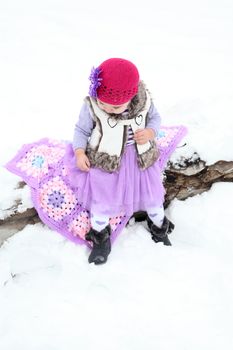 Little girl sitting outside in the snow