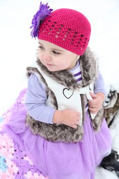Little girl sitting outside in the snow