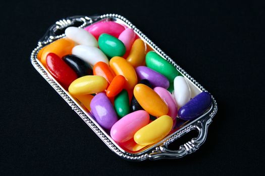 Multi colored candies on a tray with black background