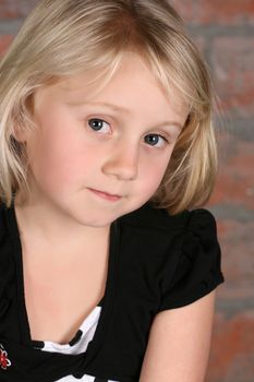 Little blond girl against a brick background