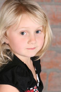 Little blond girl against a brick background