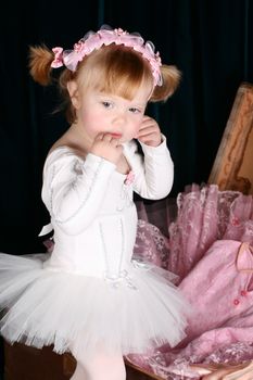 Sweet little ballet girl unpacking a suitcase with costumes