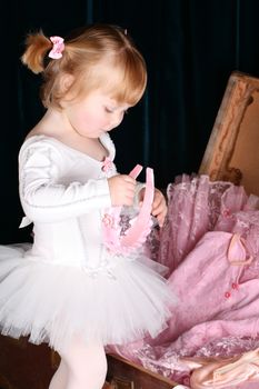 Sweet little ballet girl unpacking a suitcase with costumes