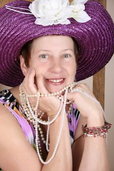 Mature female wearing a purple hat and jewellery