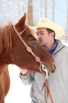 Young cowboy with his horse in a snow forest