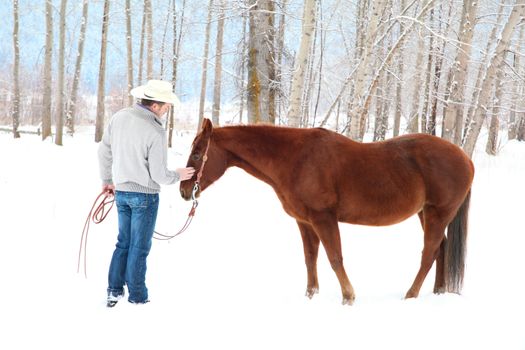 Young cowboy with his horse in a snow forest