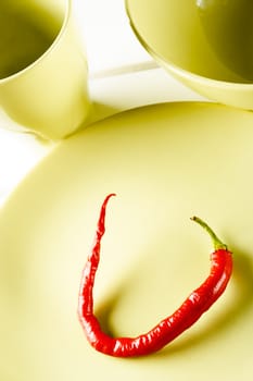 Top view red hot pepper on green dish over white wood. Vertical image.