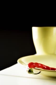  Red hot pepper on green dish over white wood. Vertical image.