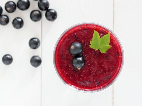 Delicious black currant smoothie with fresh berries on white wood background. Top view or flat lay