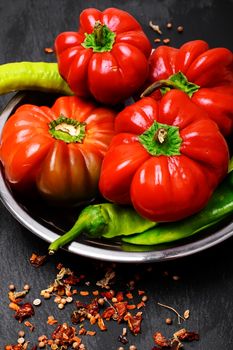 Peppers and bell peppers on a dark background studded with spicy sauce