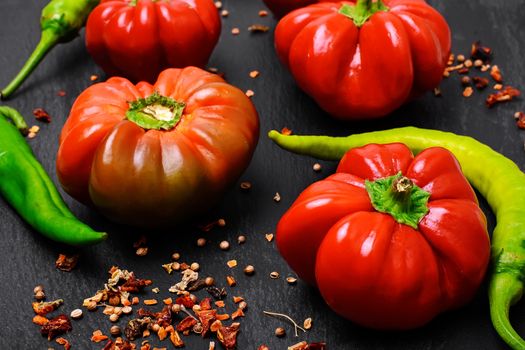 Peppers and bell peppers on dark background studded with spicy sauce