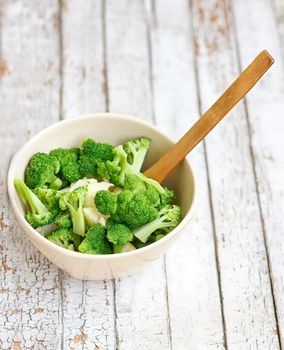 Salad in a deep bowl, broccoli, pepper and apple. On a wooden background