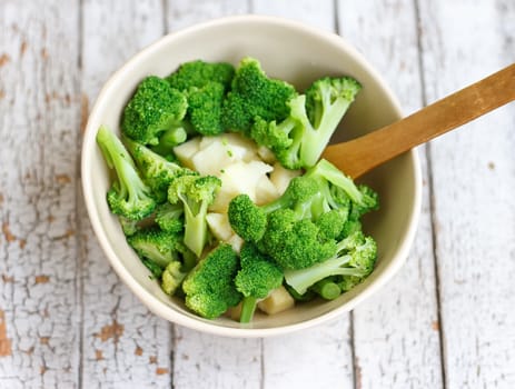 Salad in a deep bowl, broccoli, pepper and apple. On a wooden background