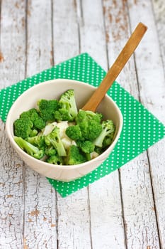Salad in a deep bowl, broccoli, pepper and apple. On a wooden background