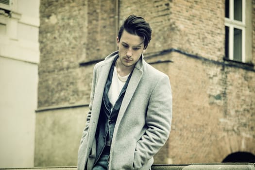 Elegant attractive young man outdoor wearing wool coat, in European city
