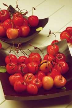 Fresh Ripe Sweet Maraschino Cherries on Black Wooden Plates closeup on Plank White background. Retro Styled