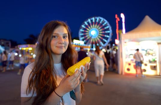 teen girl eating corn in fair