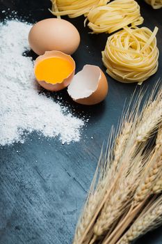 clean Food eggs, wheat flour, Pasta and barley on black wood background